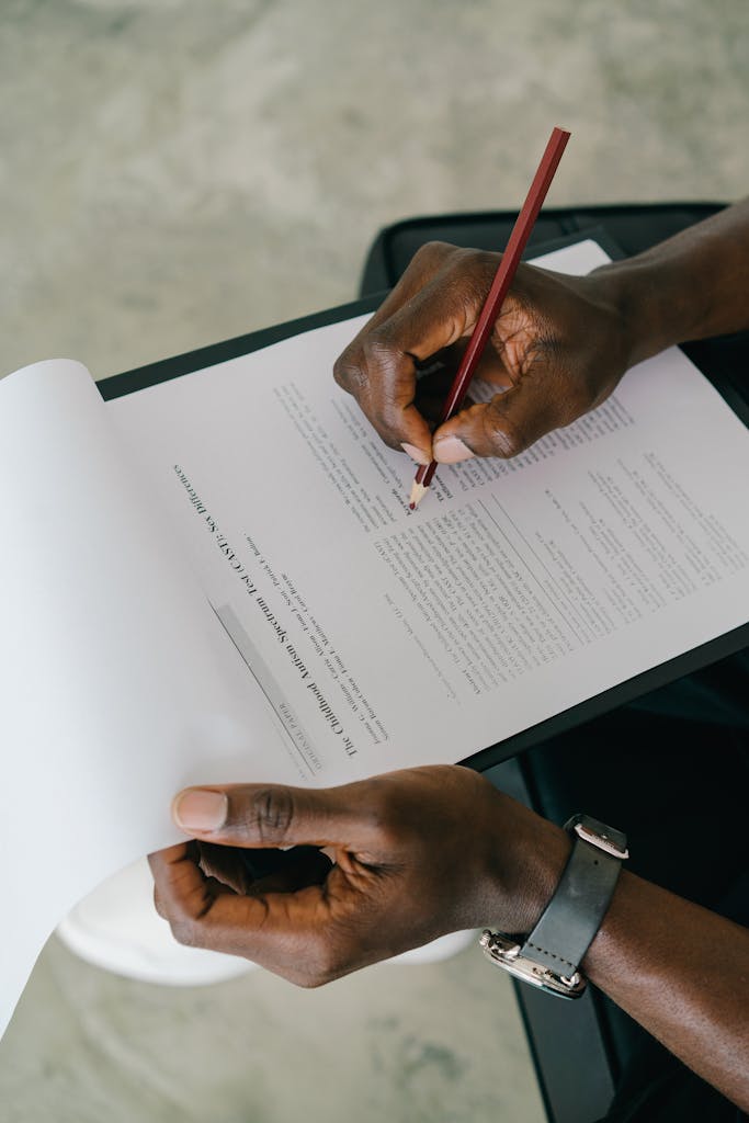 Hands holding a document and writing with a pencil, capturing a study moment.
